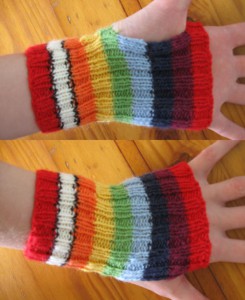 A pair of short ribbed rainbow handwarmers, with 2cm stripes in the following colours, from cuff to knuckles: red, white with black border, orange, yellow, green, blue, indigo, violet, red.